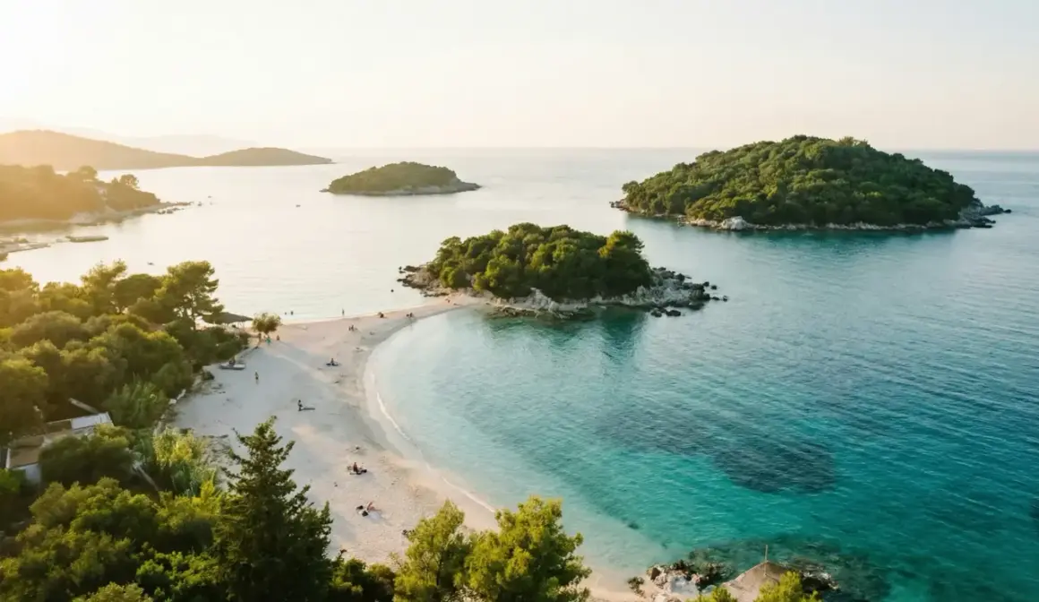Vacker strand med turkost vatten och gröna öar. Perfekt för en resa till Albanien med tips om sol och bad.