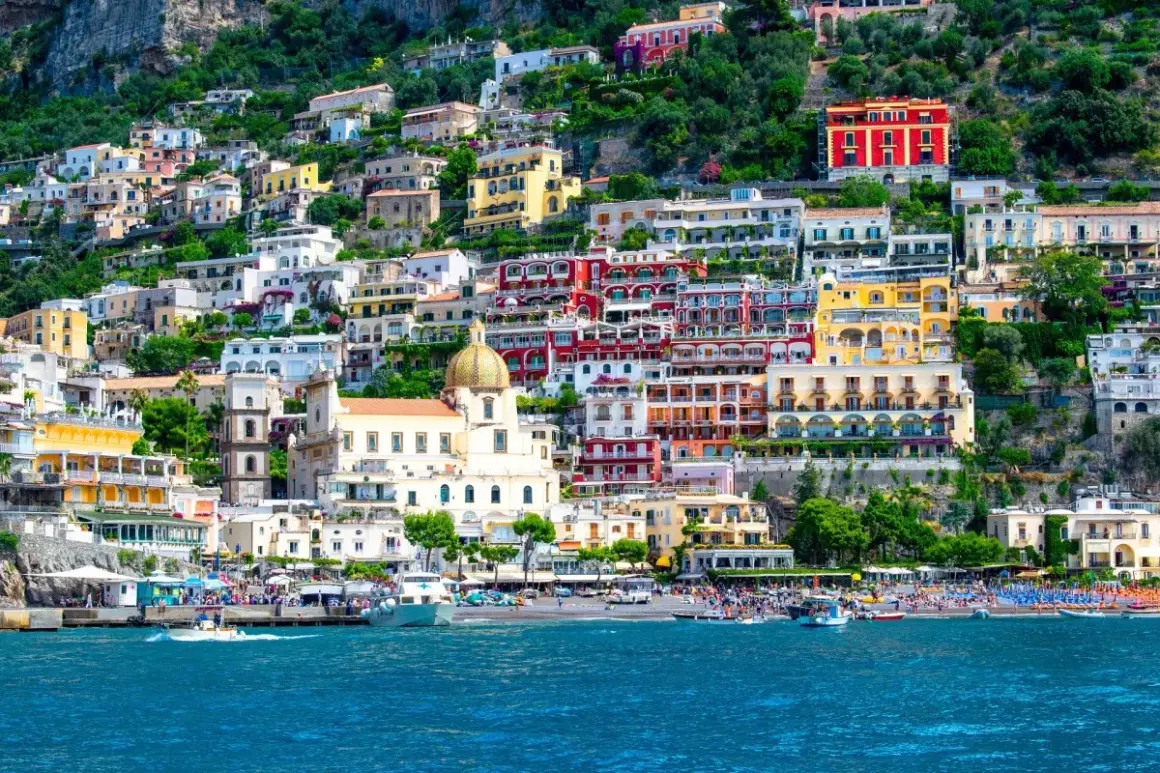 Färgstarka hus klättrar uppför en bergssluttning vid havet, en perfekt vy för en weekend i Italien.