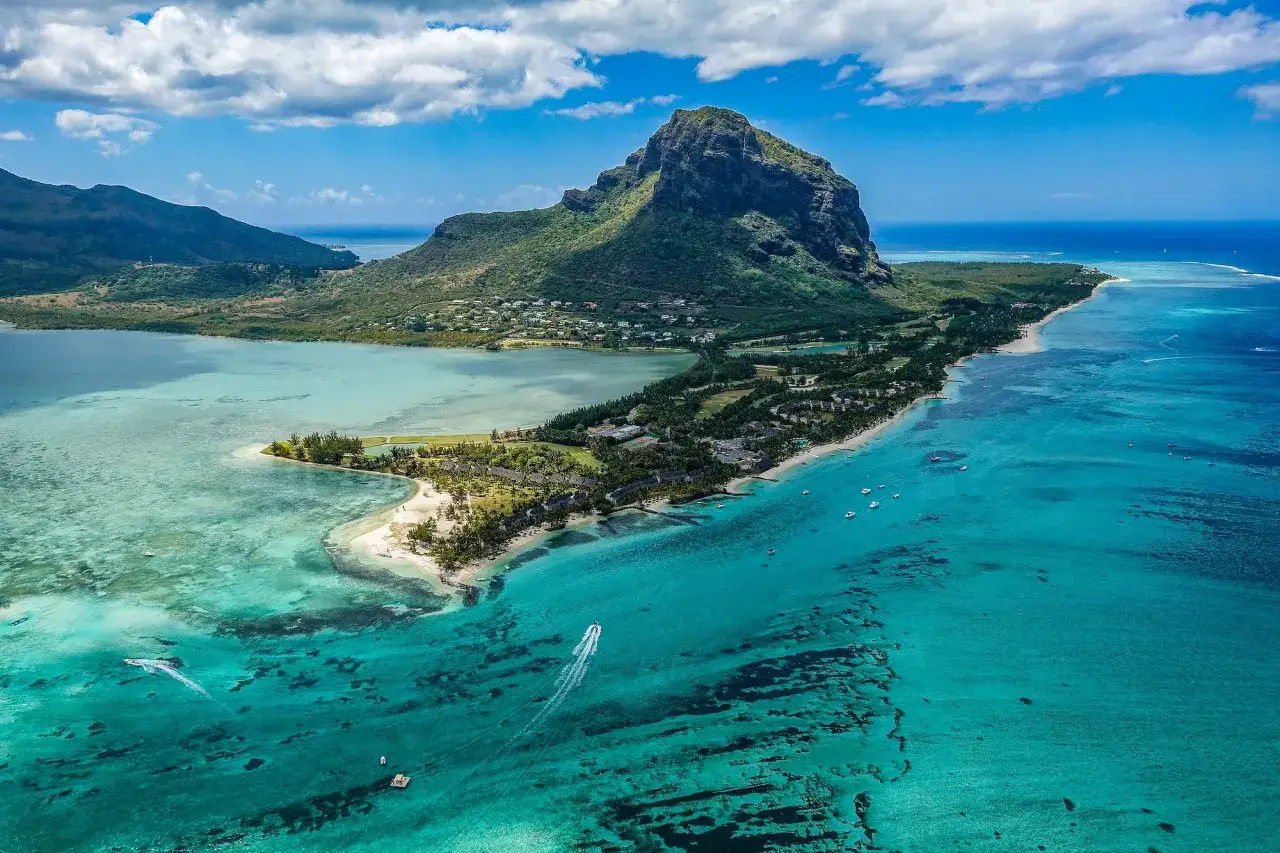 Drömmer du om att åka till Mauritius? Här ser du en fantastisk vy över Le Morne Brabant med turkost vatten och frodig grönska.