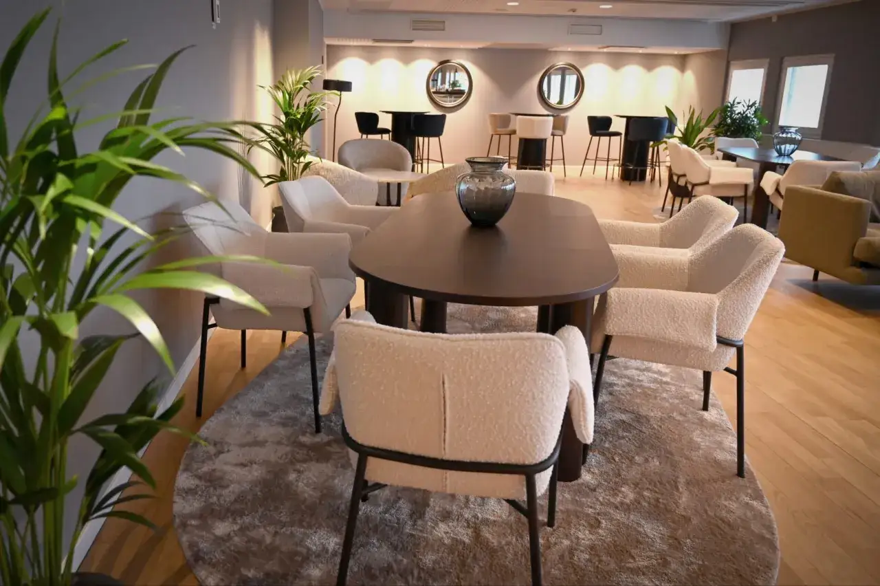 TUI Lounge Arlanda: Mysiga f&aring;t&ouml;ljer runt ett m&ouml;rkt bord, med en stor gr&ouml;n v&auml;xt i f&ouml;rgrunden.