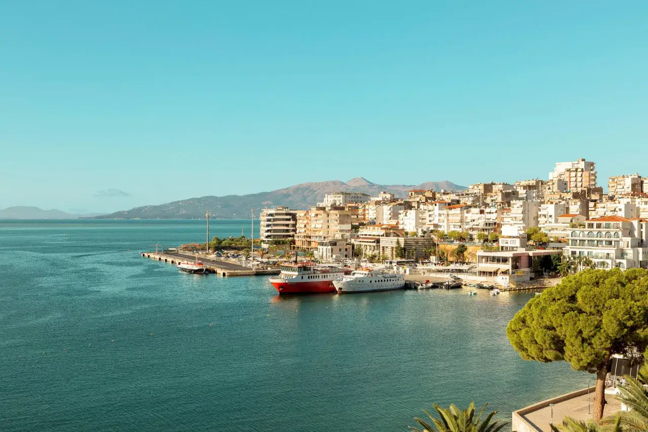 Hamnen i Sarandë, Albanien, med vita och röda fartyg vid kajen. Perfekt för dig som söker resa till Albanien tips.