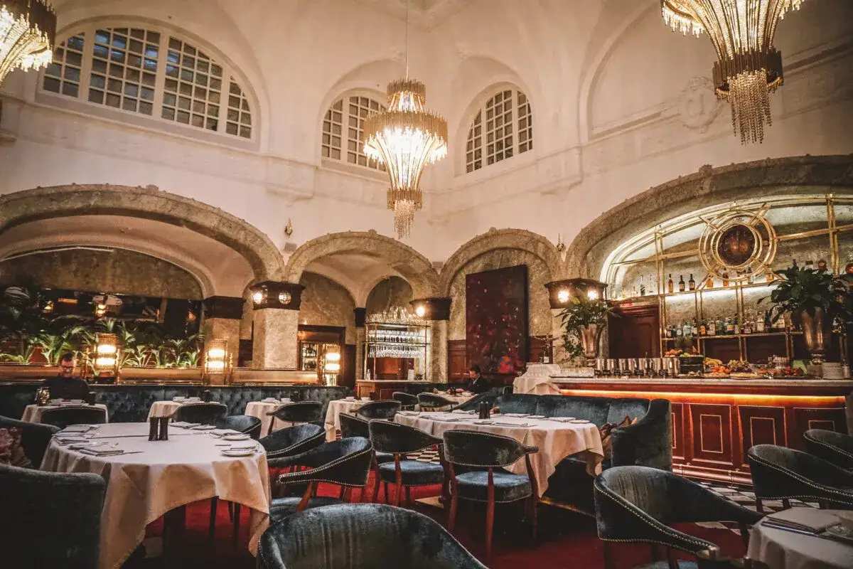 Elegant bank hotel lunch setting with plush seating, chandeliers, and a well-stocked bar.