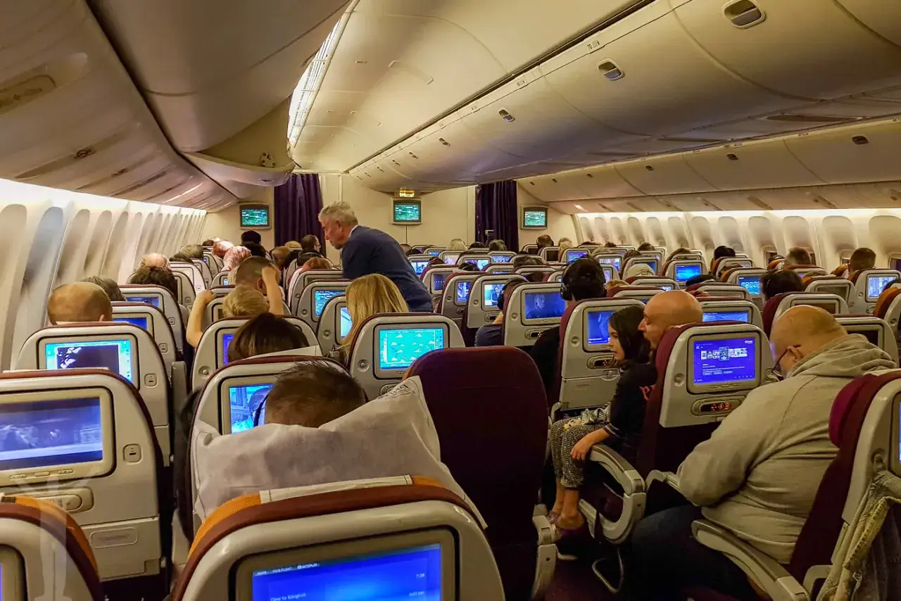 Fullt flyg p&aring; v&auml;g till Thailand. Passagerare sitter p&aring; sina platser med sk&auml;rmar framf&ouml;r sig.