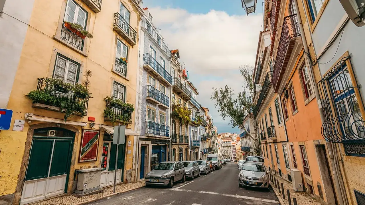 F&auml;rgglada hus l&auml;ngs en kullerstensgata i Lissabon, perfekt f&ouml;r weekendresor i Europa.