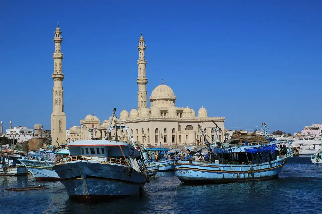 Fiskebåtar i hamnen i Hurghada, Egypten, med en stor moské i bakgrunden.
