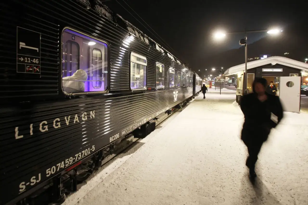 Ett mörkt liggvagnståg står på en snötäckt station. Kanske är det på väg mot Berlin från Stockholm.