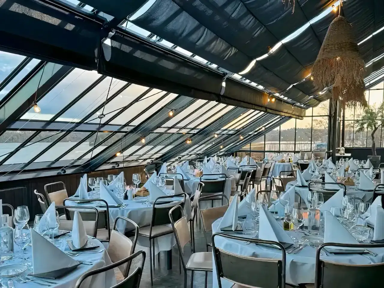 Vacker matsal med dukade bord och utsikt över vattnet på restaurang Kolmilan.