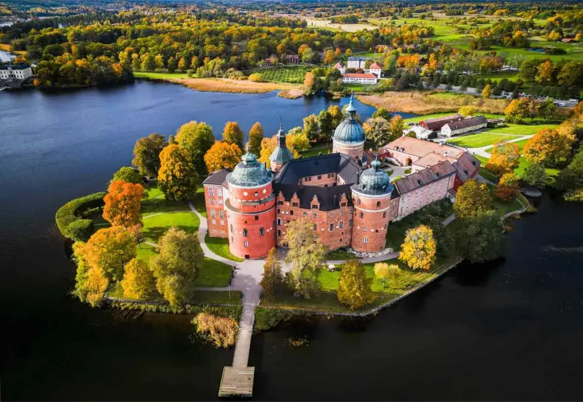 Vackert slott vid en sjö, perfekt för utflykter i Stockholm med höstens färger.